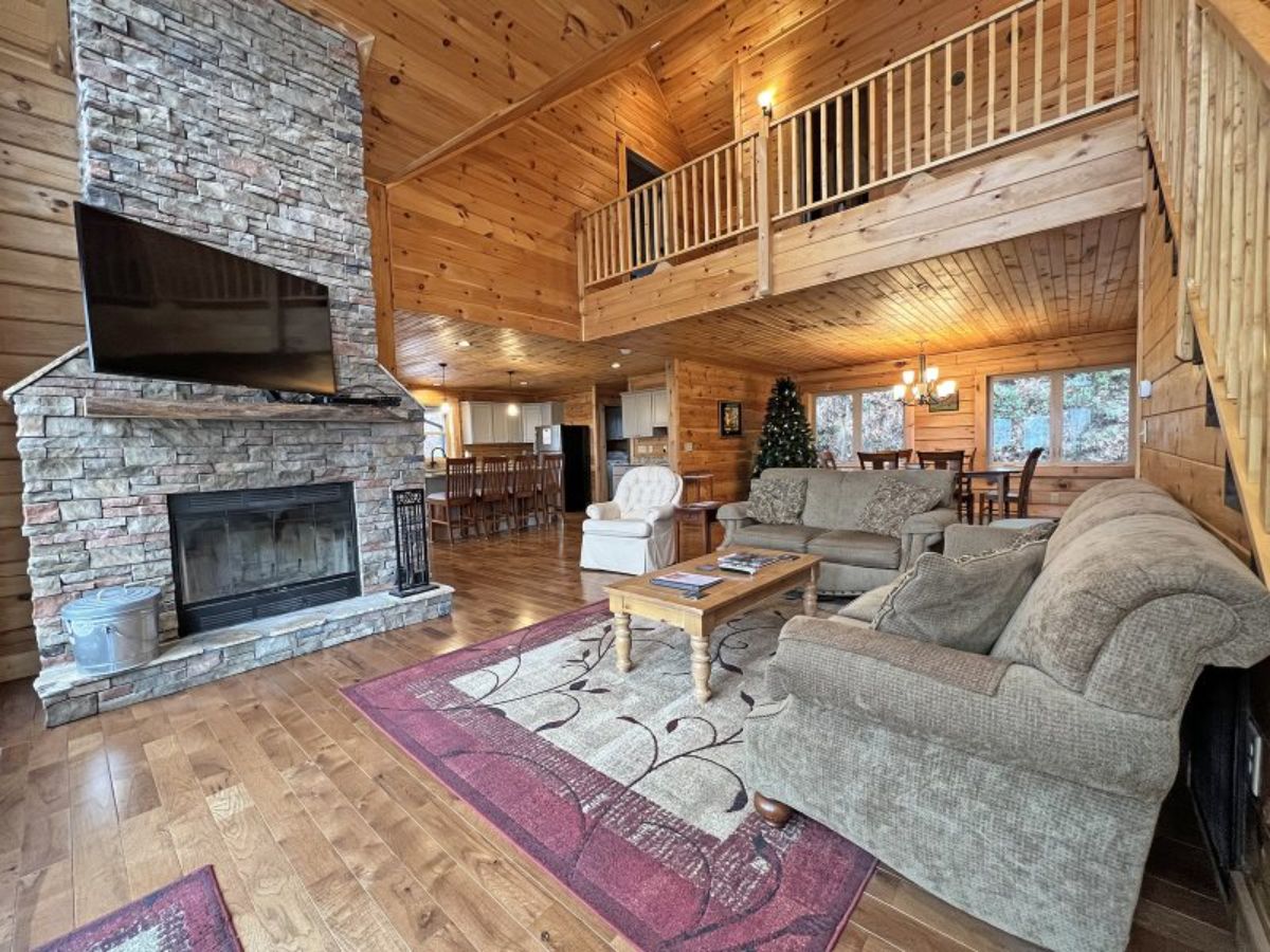 light brown sofa on red and white rug with fireplace in left corner