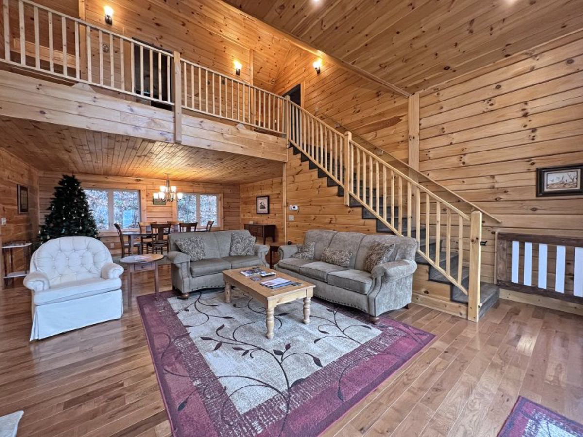 stairs to loft behind light brown sofas on red and white rug