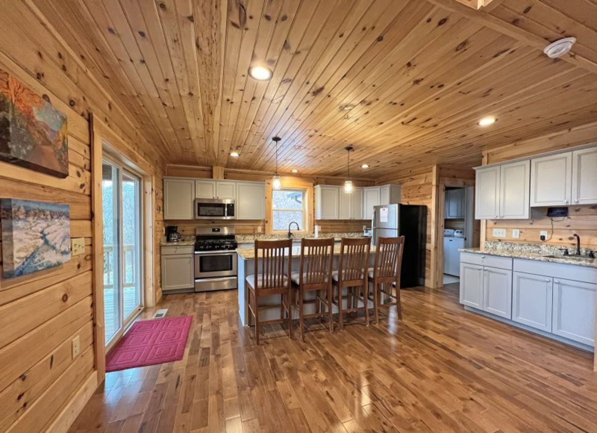 chairs against bar in kitchen with red rug by door on left