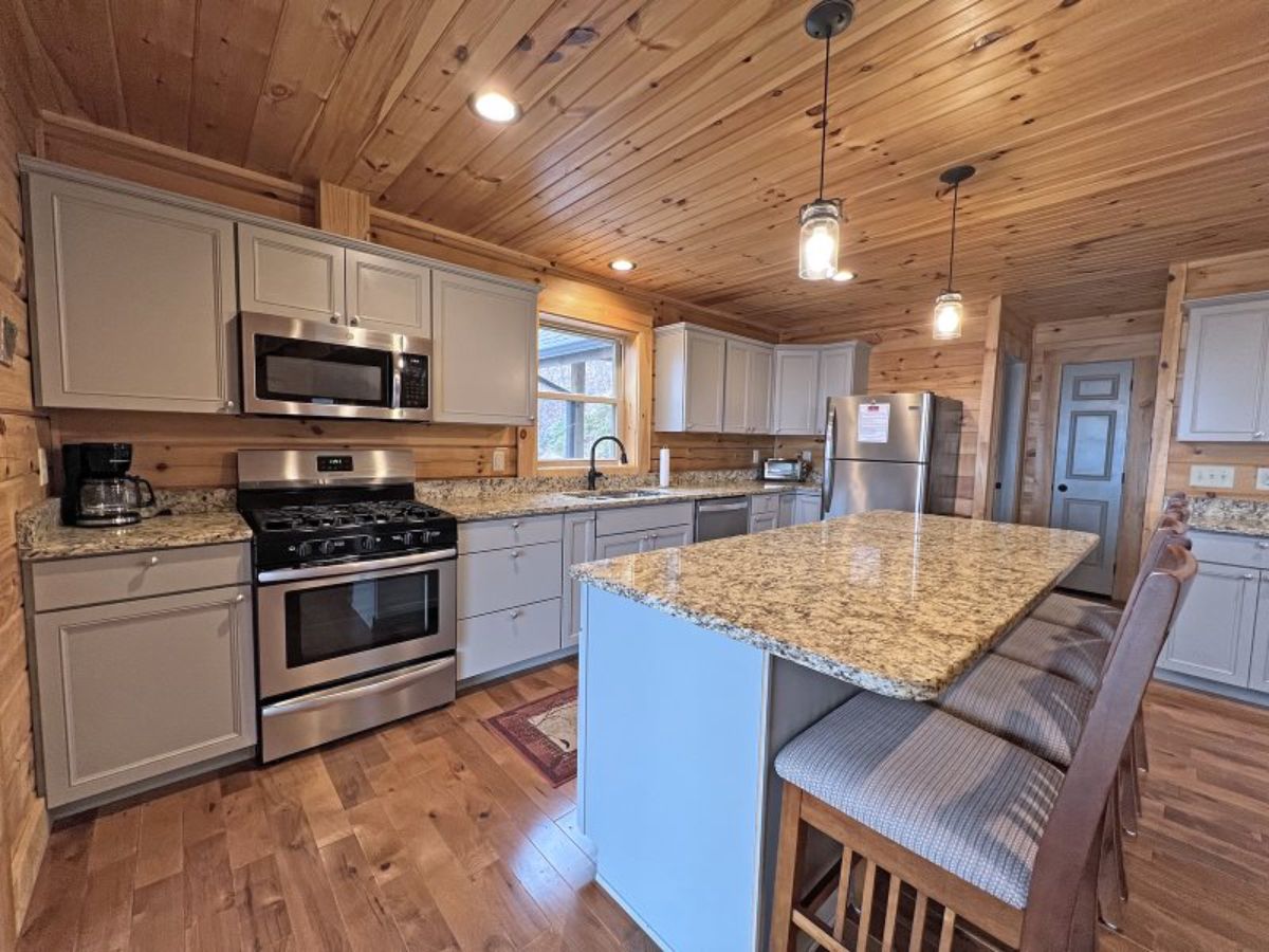 stainless steel stove in white cabinets with island bar in foreground of kitchen