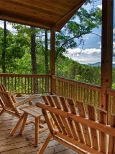 porch with adirondack chairs and roof looking over mountains and clouds in background