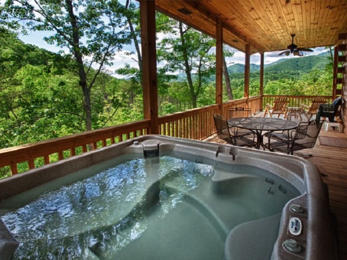 hot tub in foreground with table in background on deck overlooking treeline