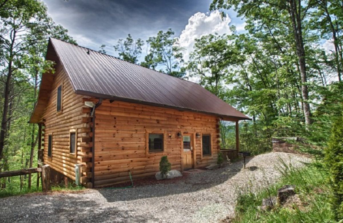 cabin with dark metal roof against cloudy sky