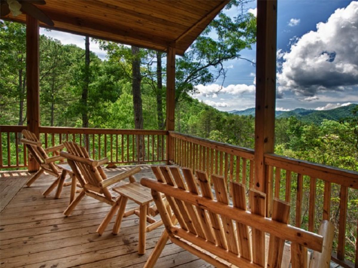 porch with adirondack chairs and roof looking over mountains and clouds in background
