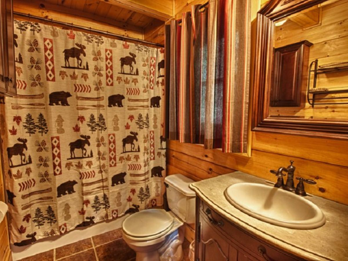 bear themed shower curtain on bathtub in log cabin bathroom