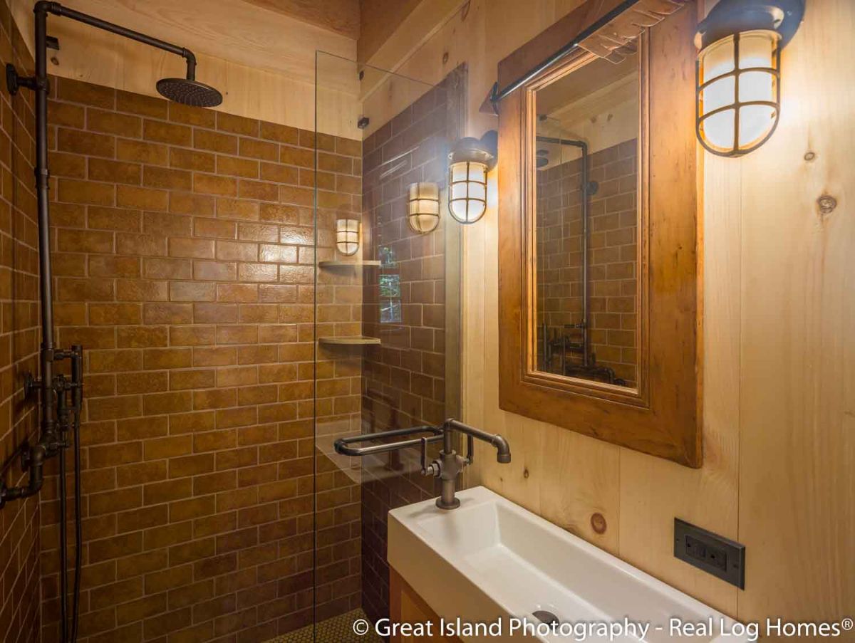 bathroom with slimline white sink against right wall and dark brown tile in shower with glass door