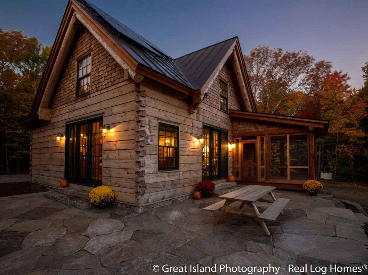 light wood log cabin after dark showing picnic table by window