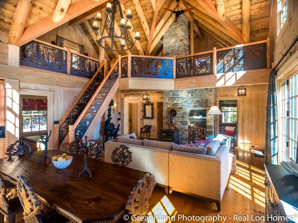 living room of log cabin with wrought iron railing on stairs and loft railing along with sofa and live edge table