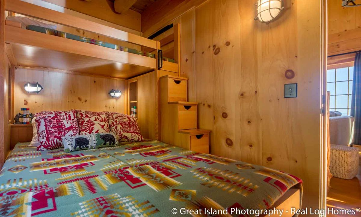 rustic green and dark red blanket on bed with stair on left to top bunk