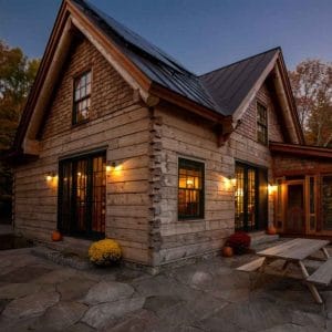 light wood log cabin after dark showing picnic table by window