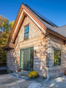 light wood exterior of log cabin with light teal accents at windows