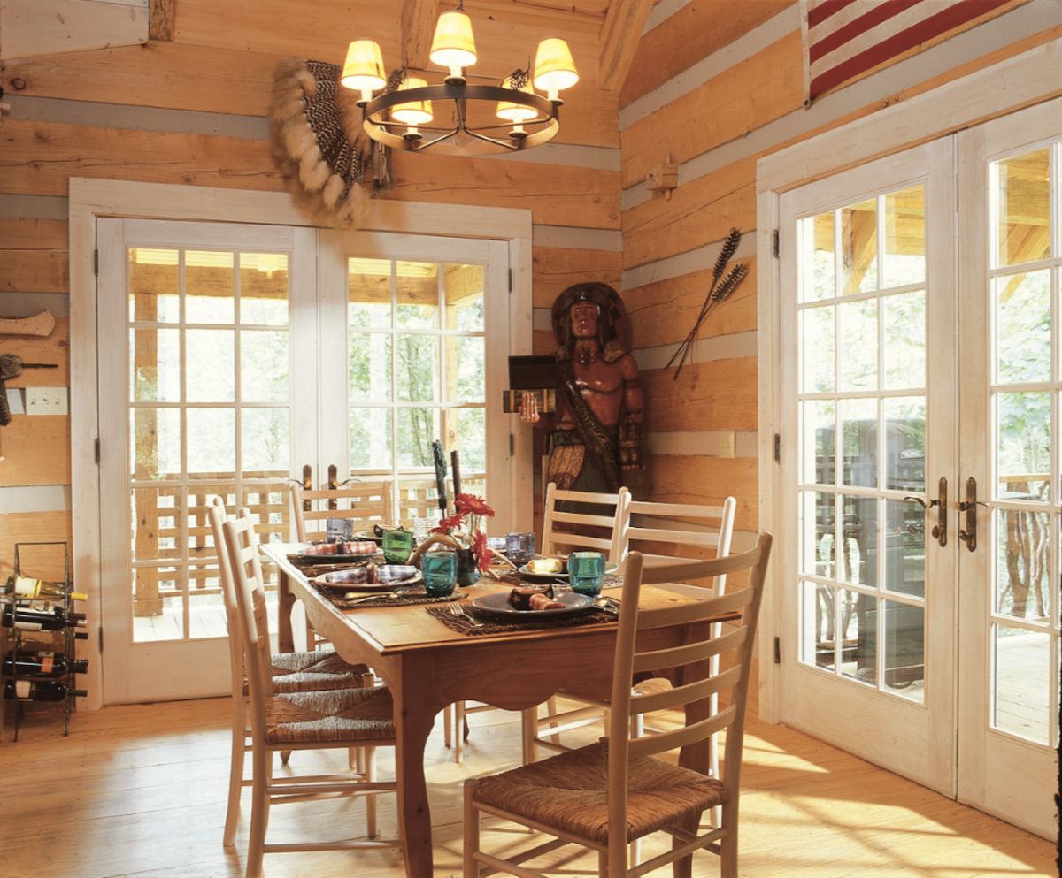 dining table in log cabin with white french doors on both sides and chandelier above table