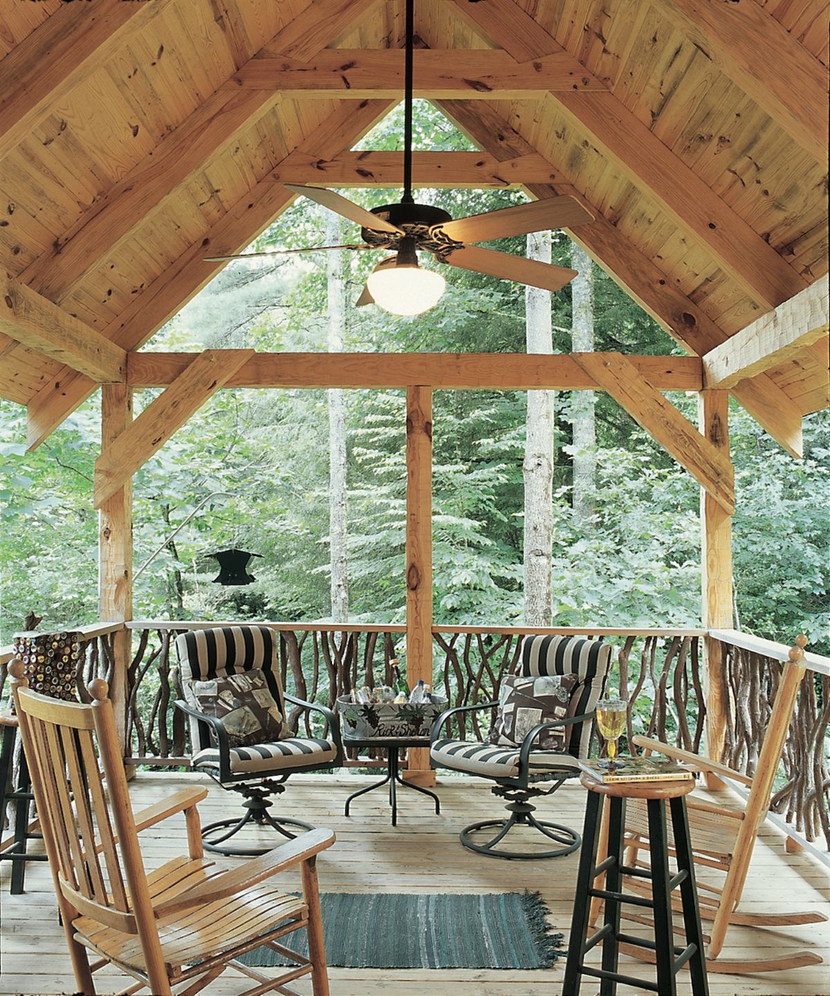 Covered porch with chairs along rail and ceiling fan