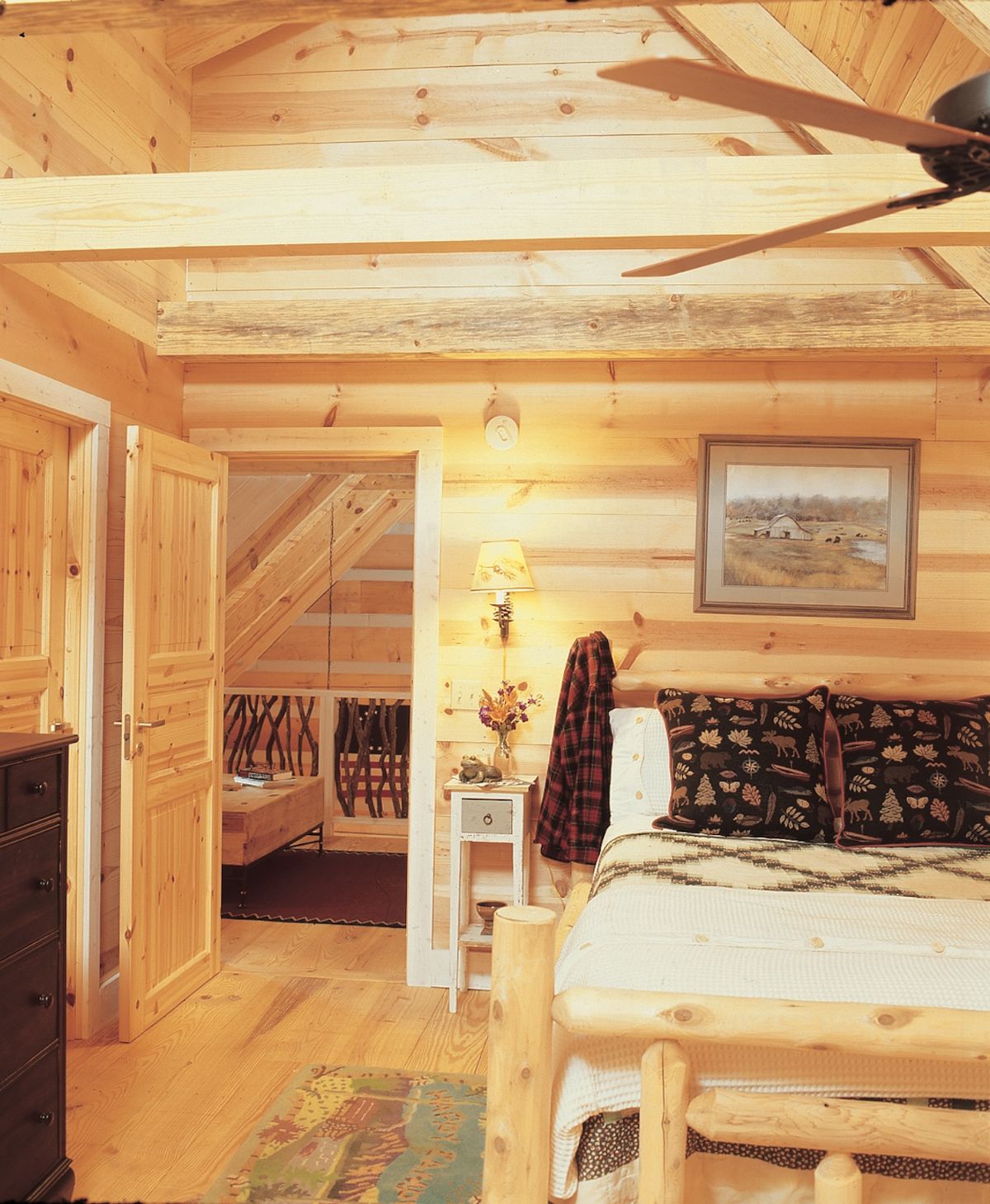 bed against light wood wall in log cabin with open door on left