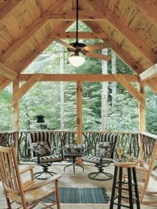 Covered porch with chairs along rail and ceiling fan