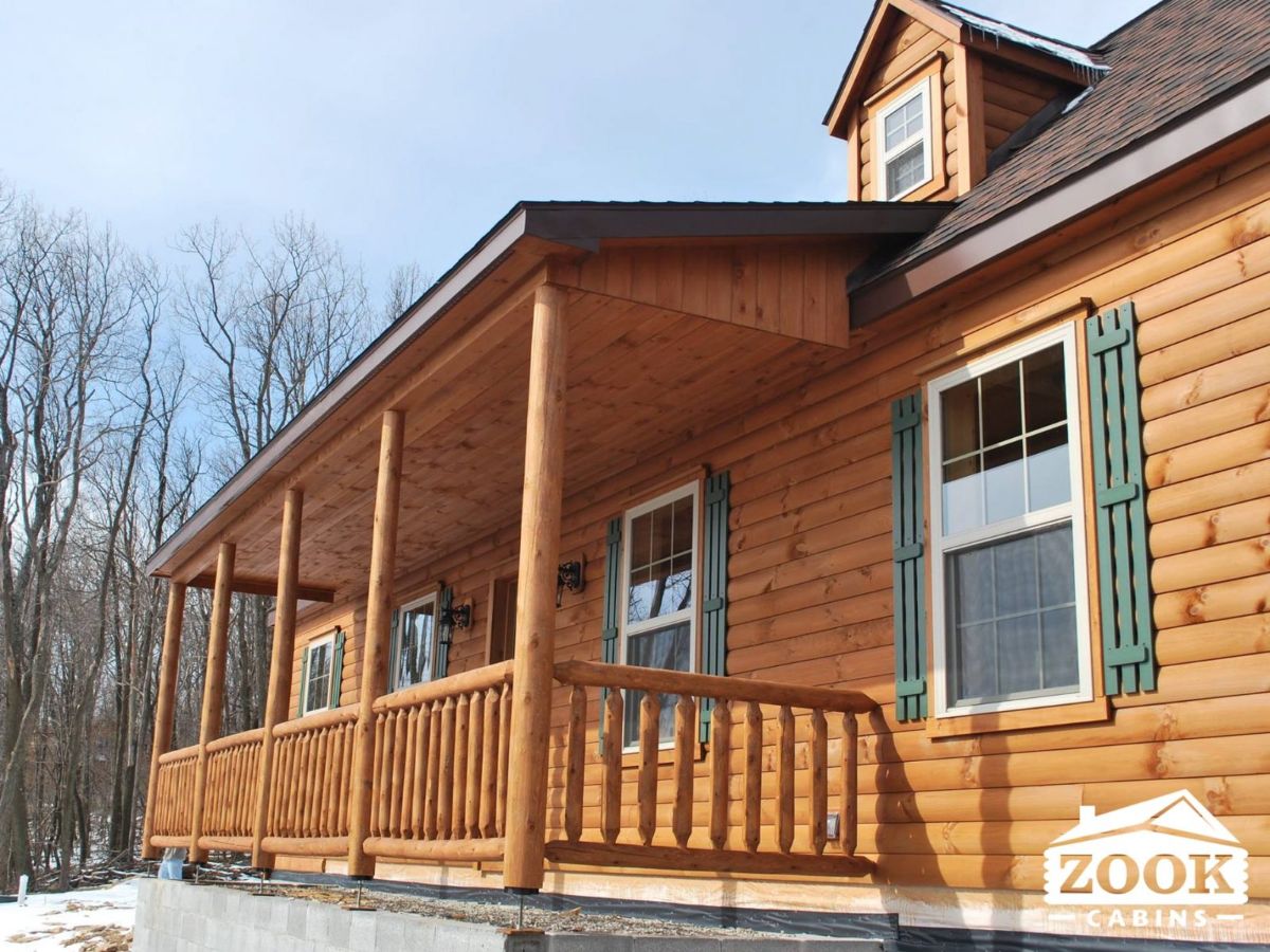 covered porch on log cabin with dormer window above