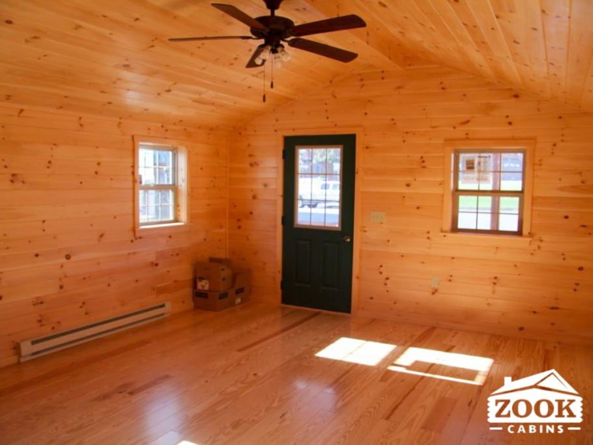 stained wood entry inside log cabin with ceiling fan in middle of room