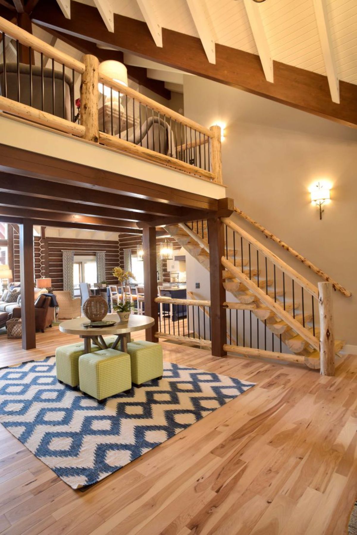 white and black rug under green table below loft with stairs on right