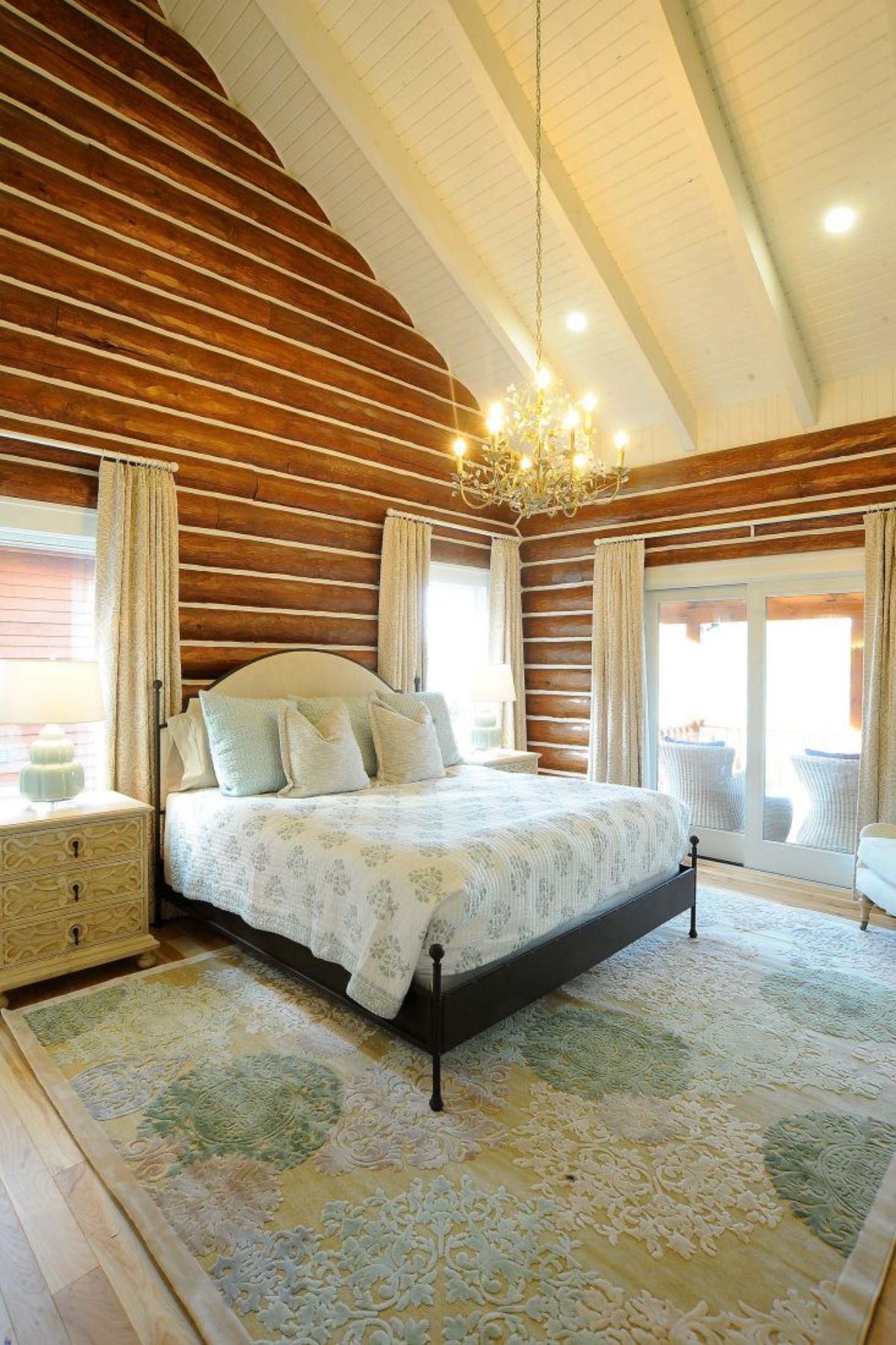 black bedframe with white bedding against chinked log wall