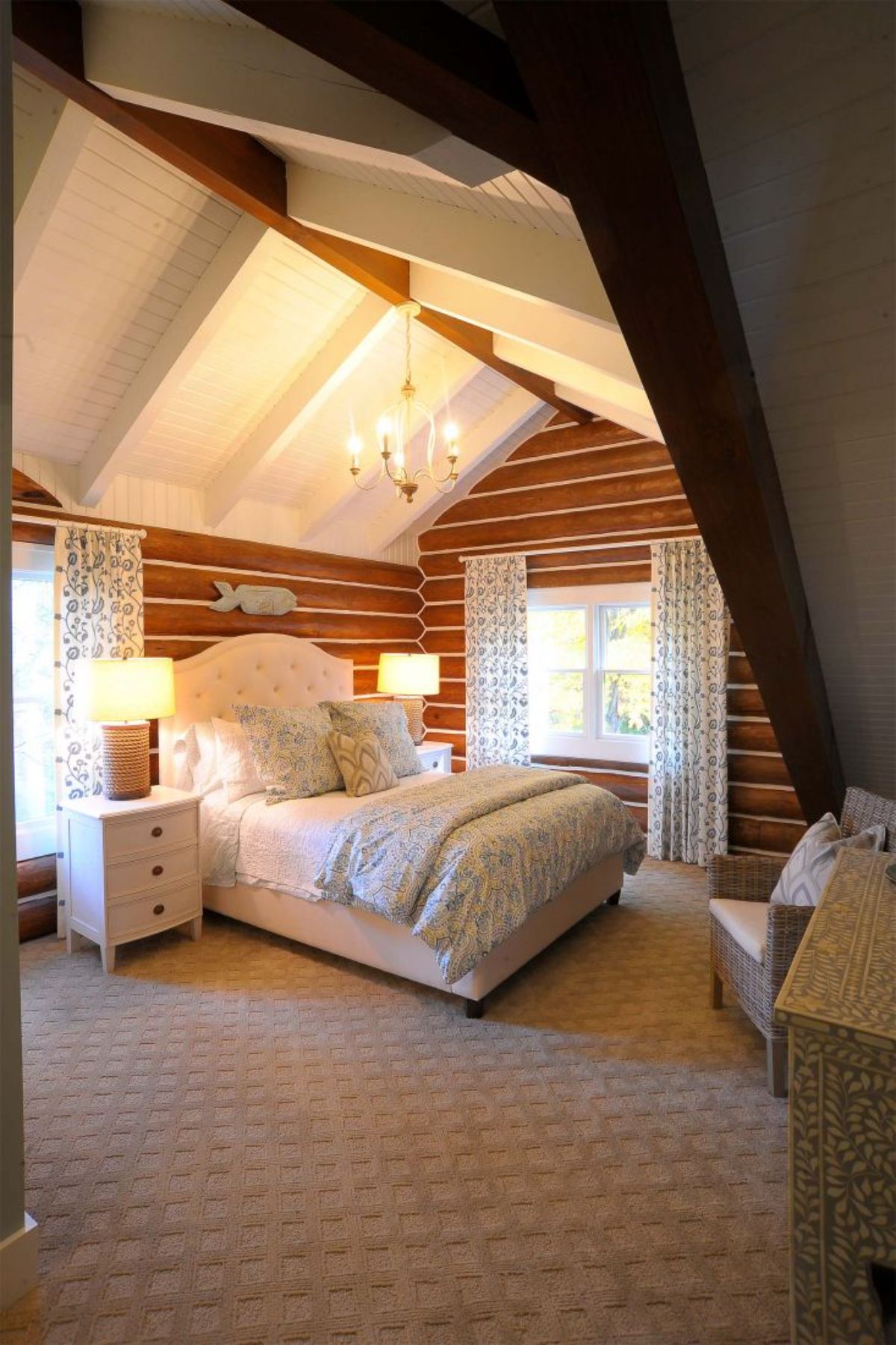 white bedding and bed frame in log cabin bedroom with chinked walls
