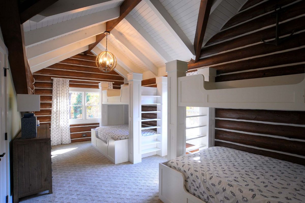white bunk beds in log cabin lofted bedroom showing white and log waslls