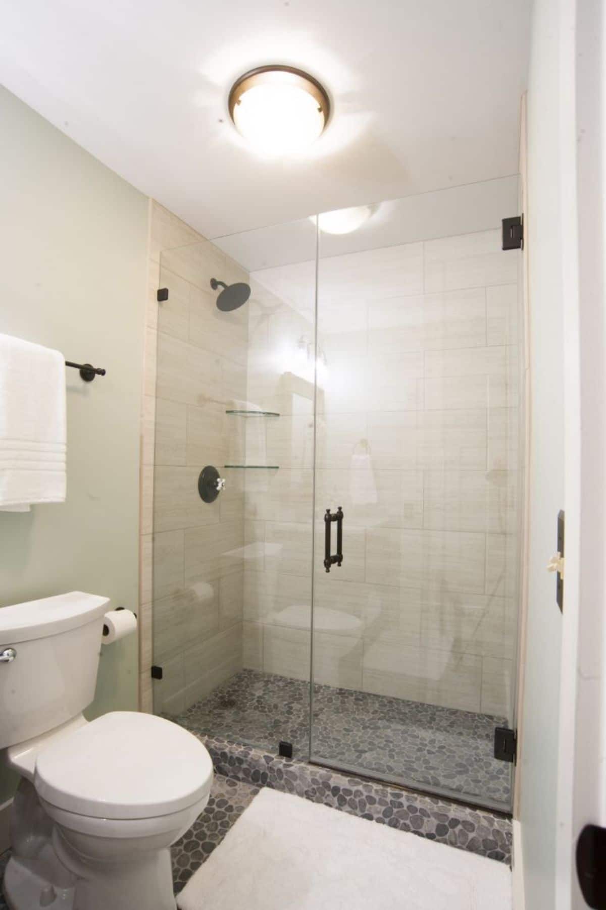 white tiled shower with glass door in back of bathroom
