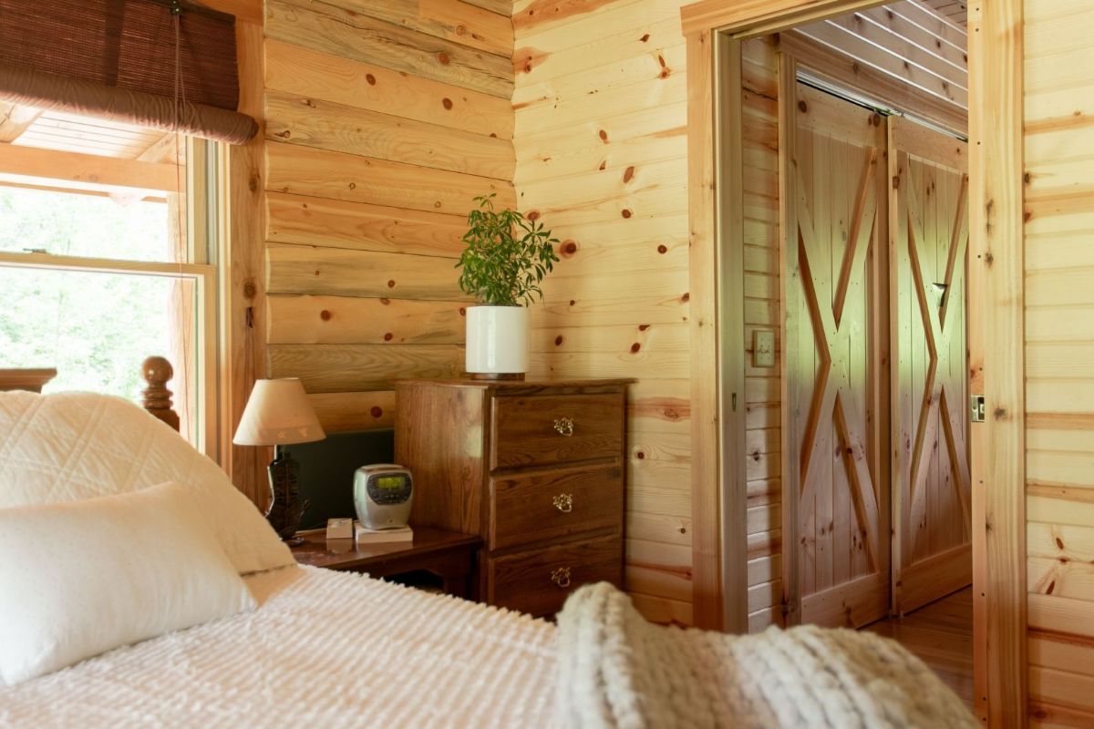 view over white bedding in bedroom to open bathroom door on right