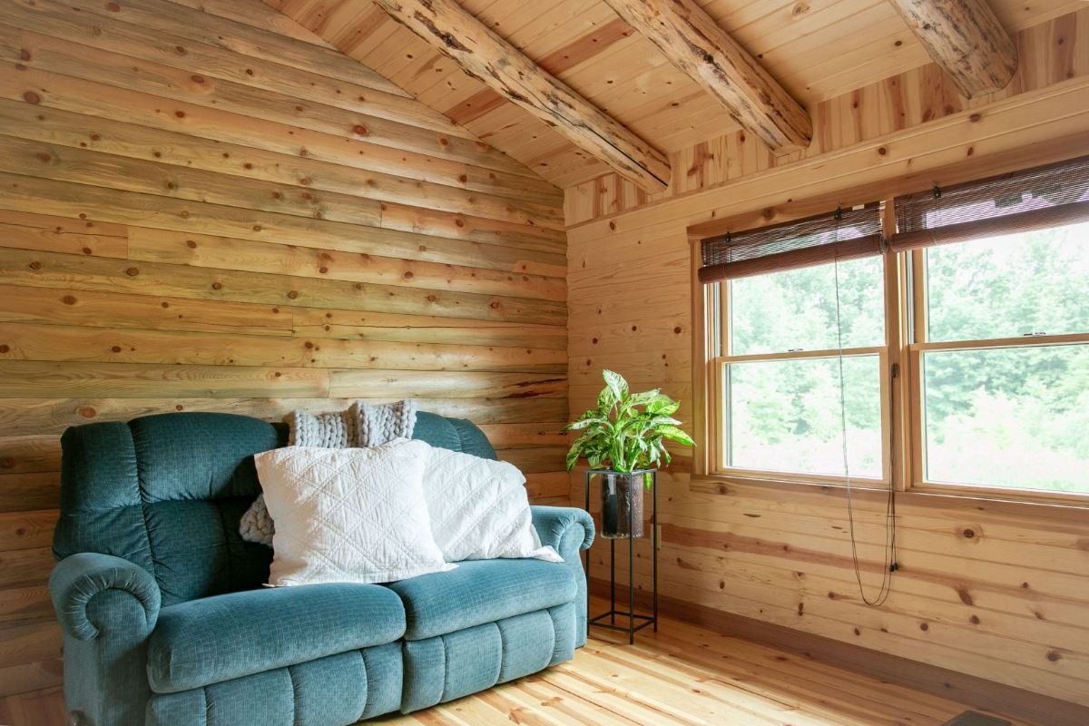 teal sofa against log wall with white pillows