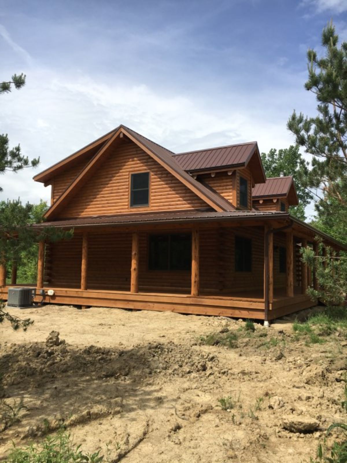 medium wood stain on log cabin with wrap around porch