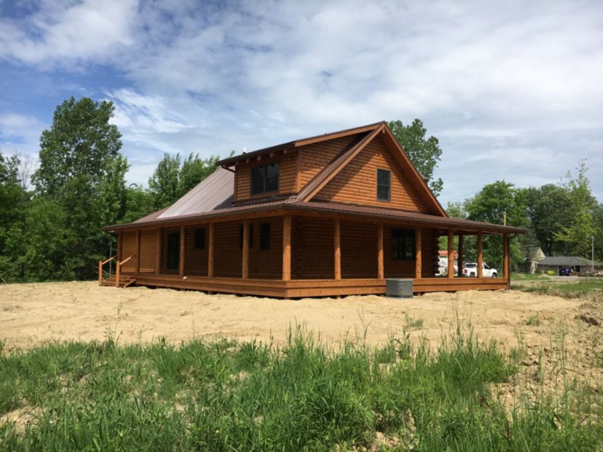 medium wood stain on log cabin with wrap around porch