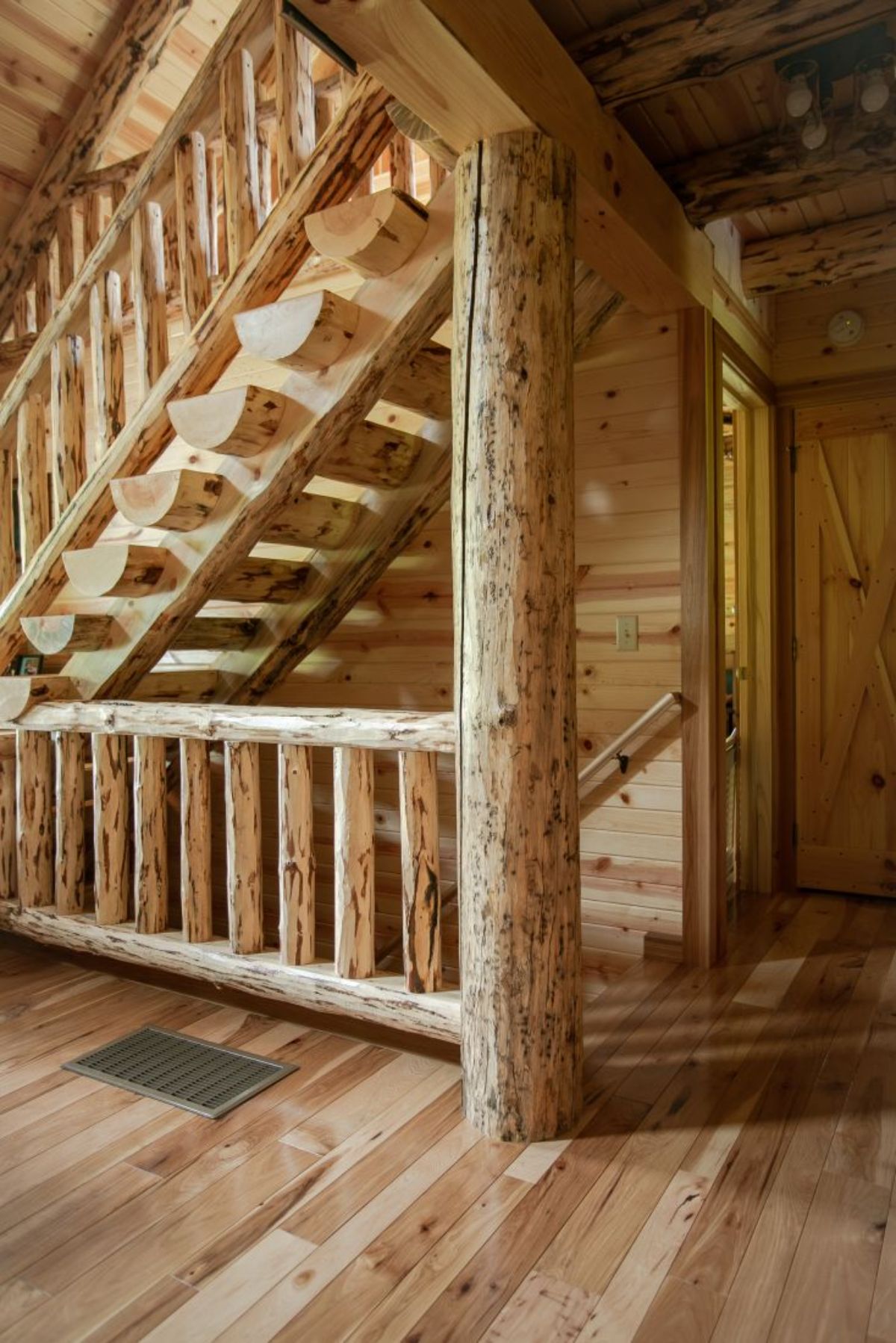 log stairs leading to loft and basement against back wall of cabin