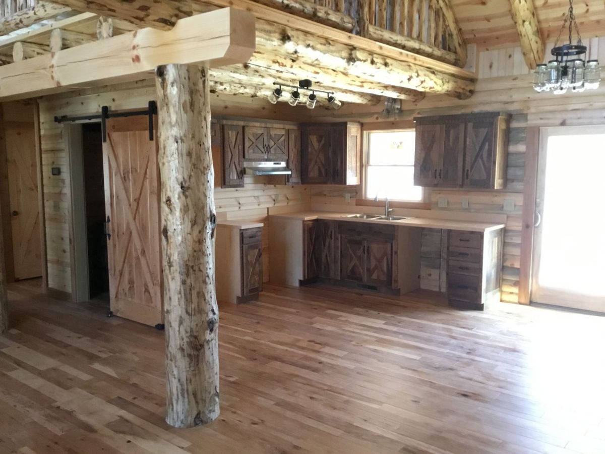 view into kitcehn with loft above and log beam in center of space