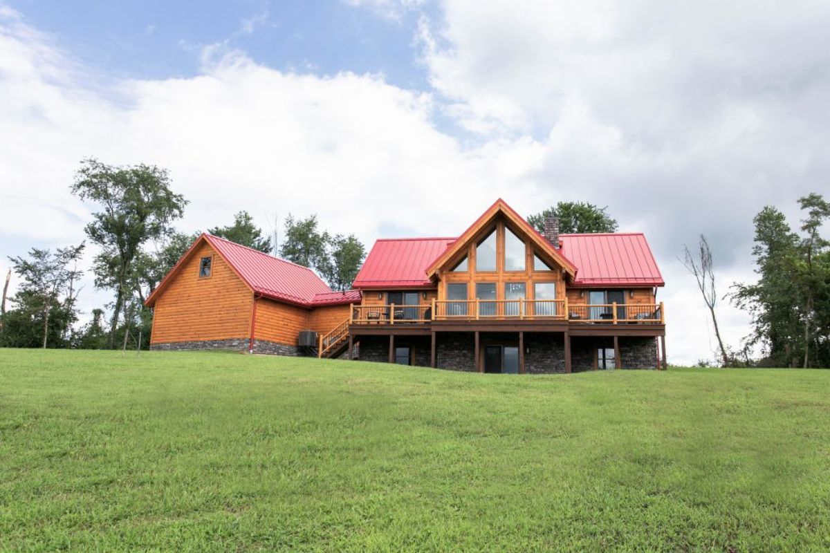 sprawling log cabin on hill with red roof