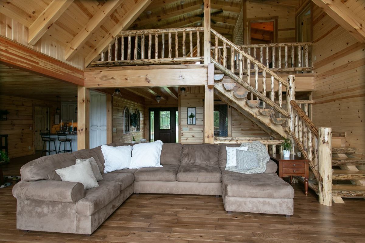 brown sofa underneath open loft in log cabin man floor