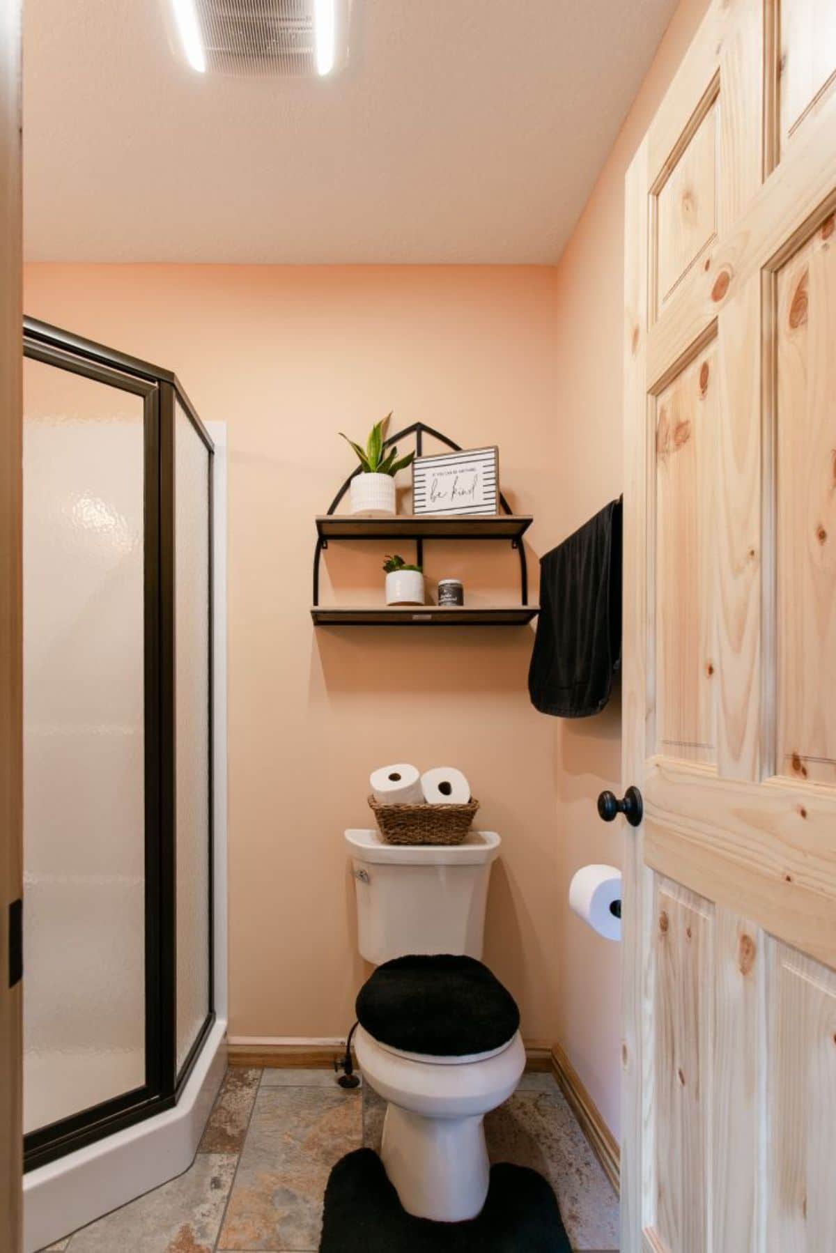 black cover on white toilet with black trim around shower on left