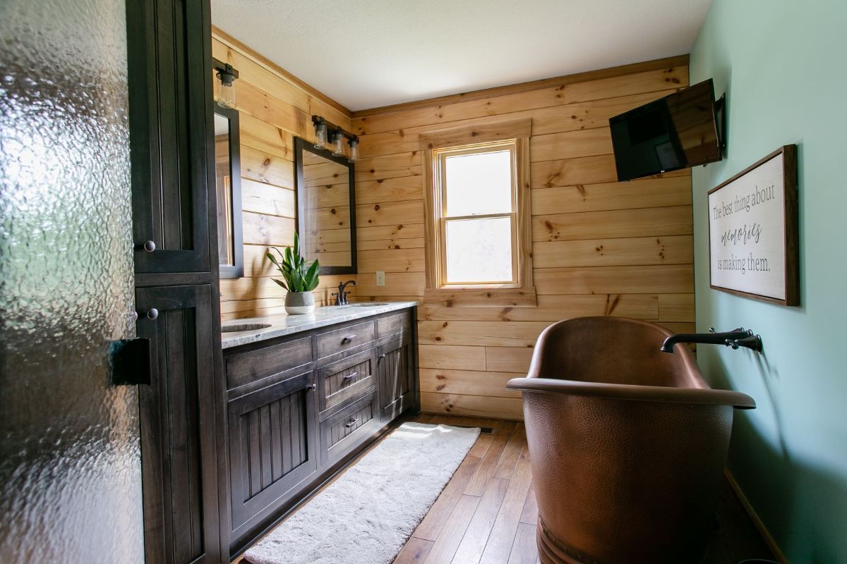 copper bathtub on right with dark wood cabinets on left