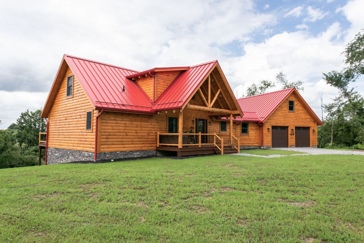 front porch of log cabin with red roof and 2 car garage on right side