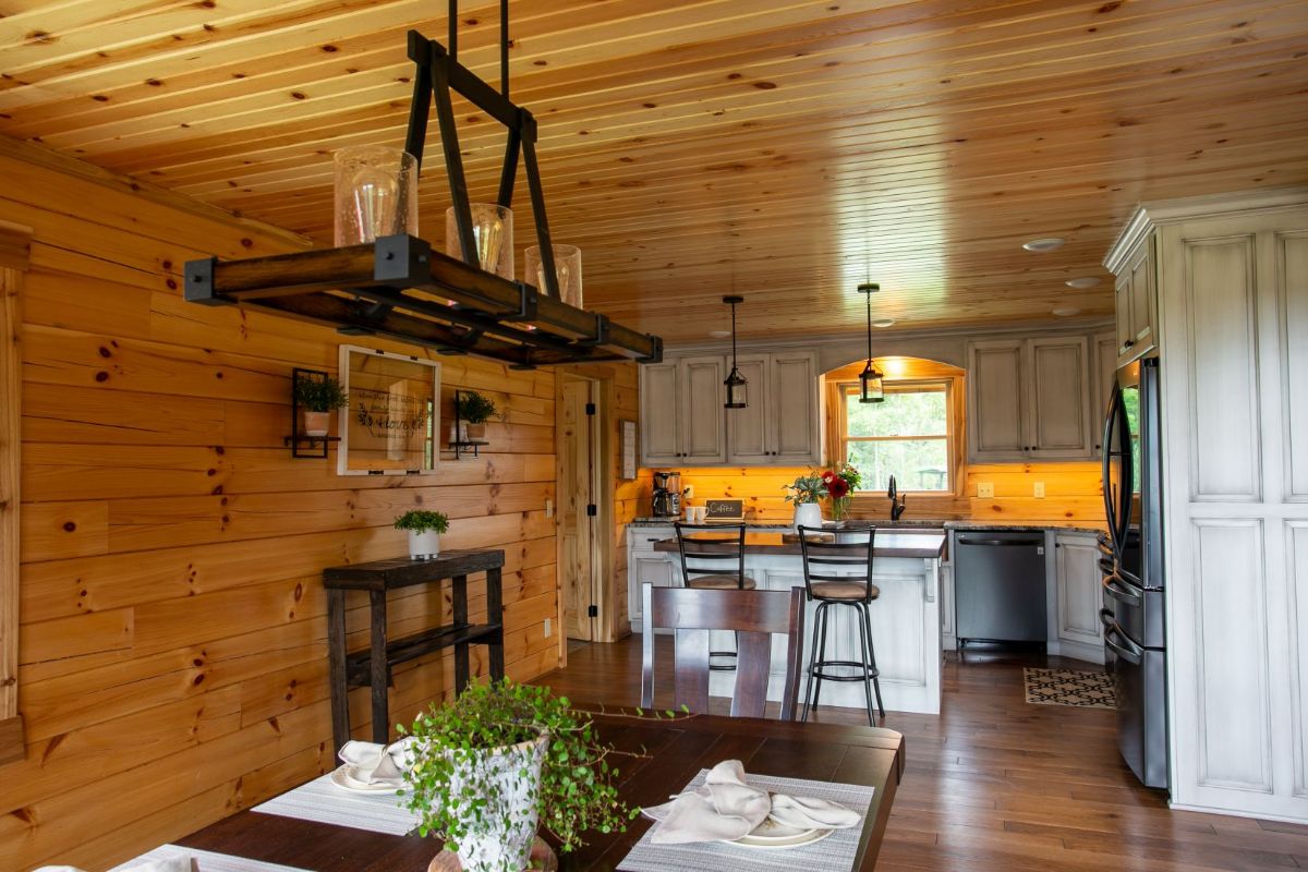 dark wood table under chandelier with kitchen in background