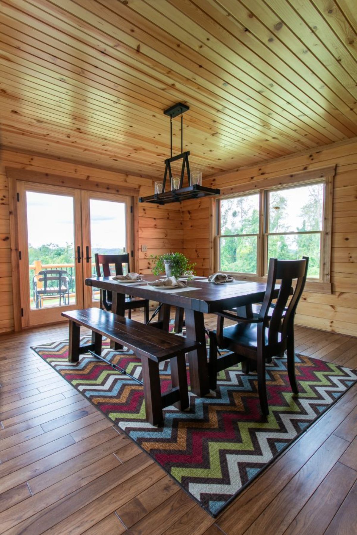 dark wood table with chairs and bench on zig zag rug with windows on all sides