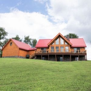 sprawling log cabin on hill with red roof