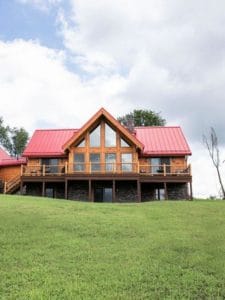 sprawling log cabin on hill with red roof