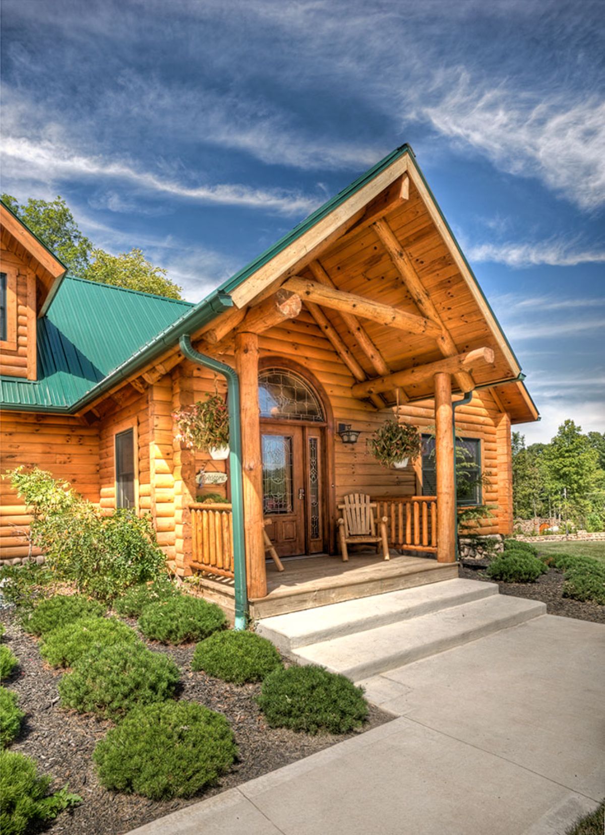 front entry of log cabin with covered porch and green roof