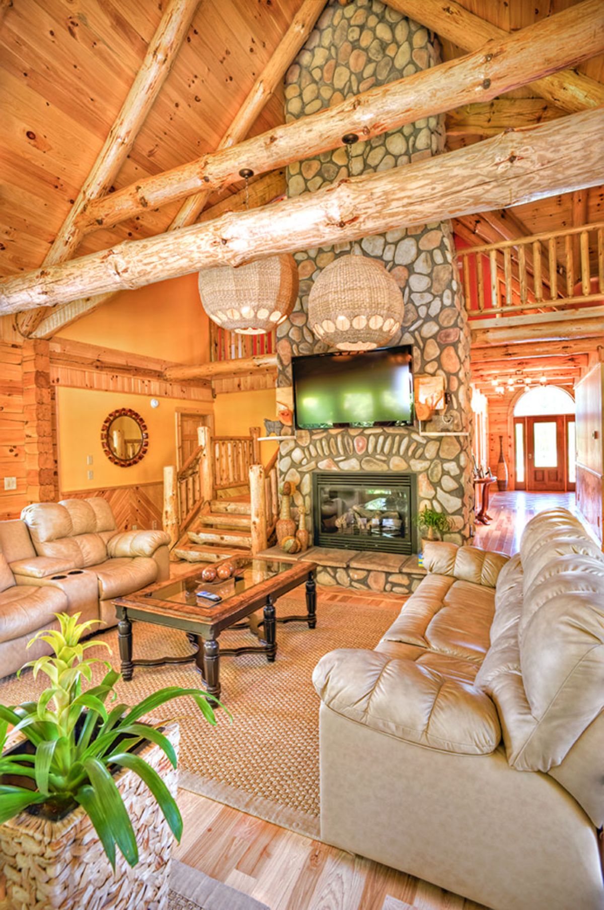 light cream leather sofa on right with stone fireplace on end of cabin living space
