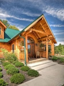front entry of log cabin with covered porch and green roof