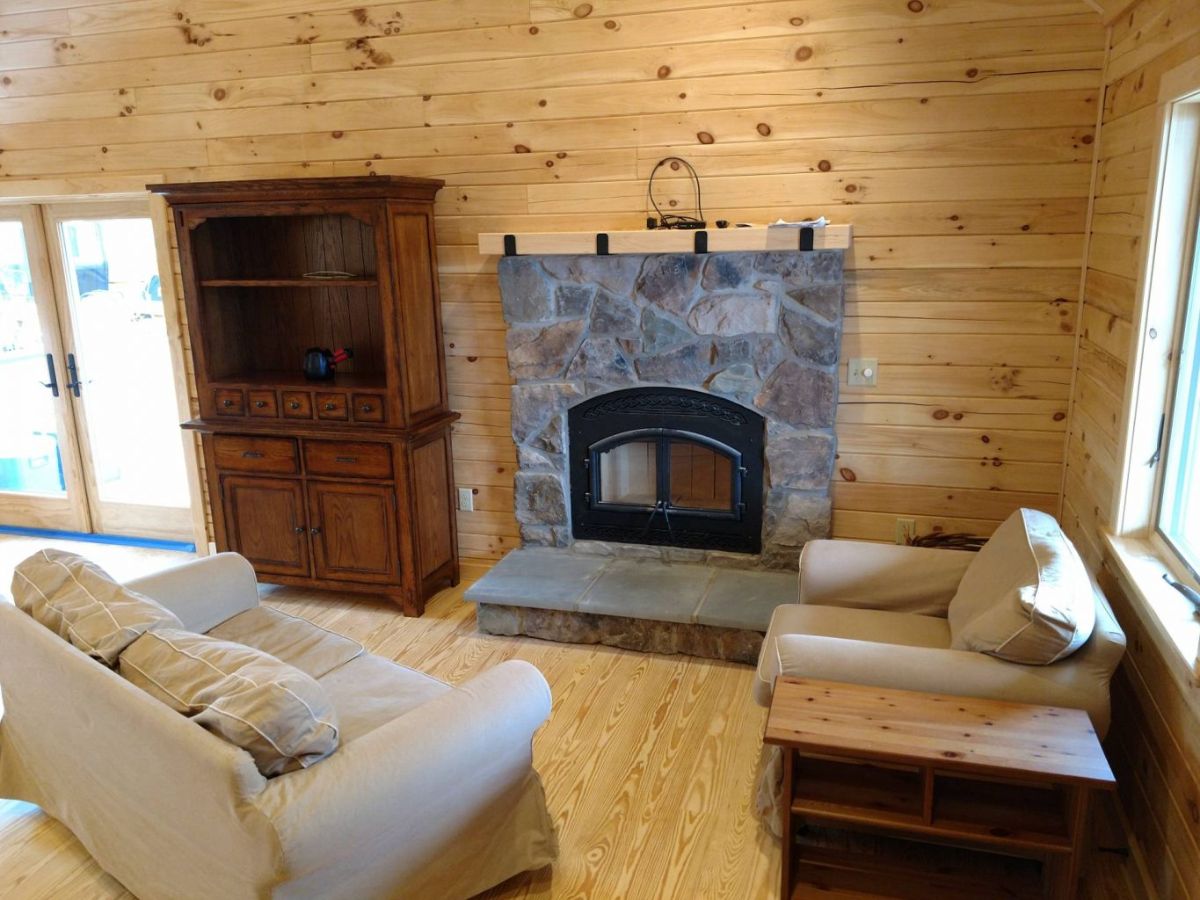 stone fireplace against light wood wall in living room with cream sofas