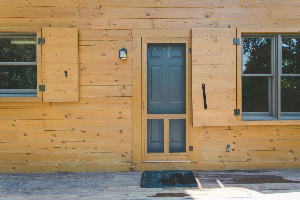 front door to cabin with screen on front and shutter to window adjacent to door