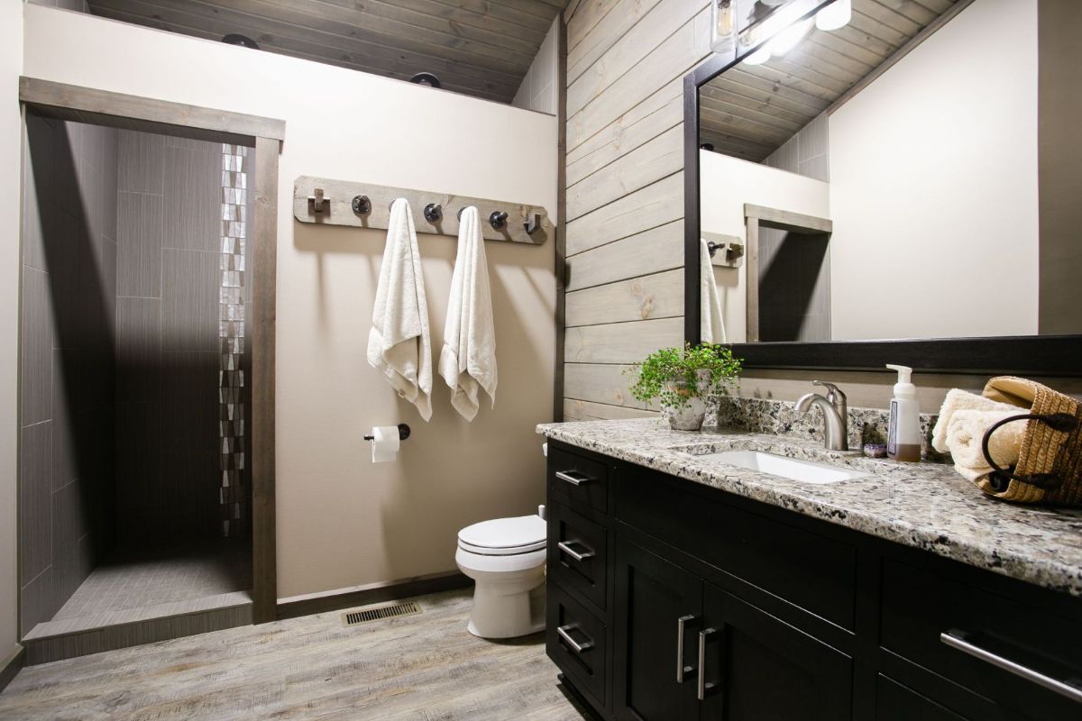 dark wood cabinets in bathroom with light gray walls and hooks against wall by shower door