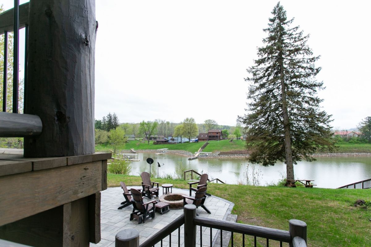 view of lake and property off back deck of log cabin showing patio seating below