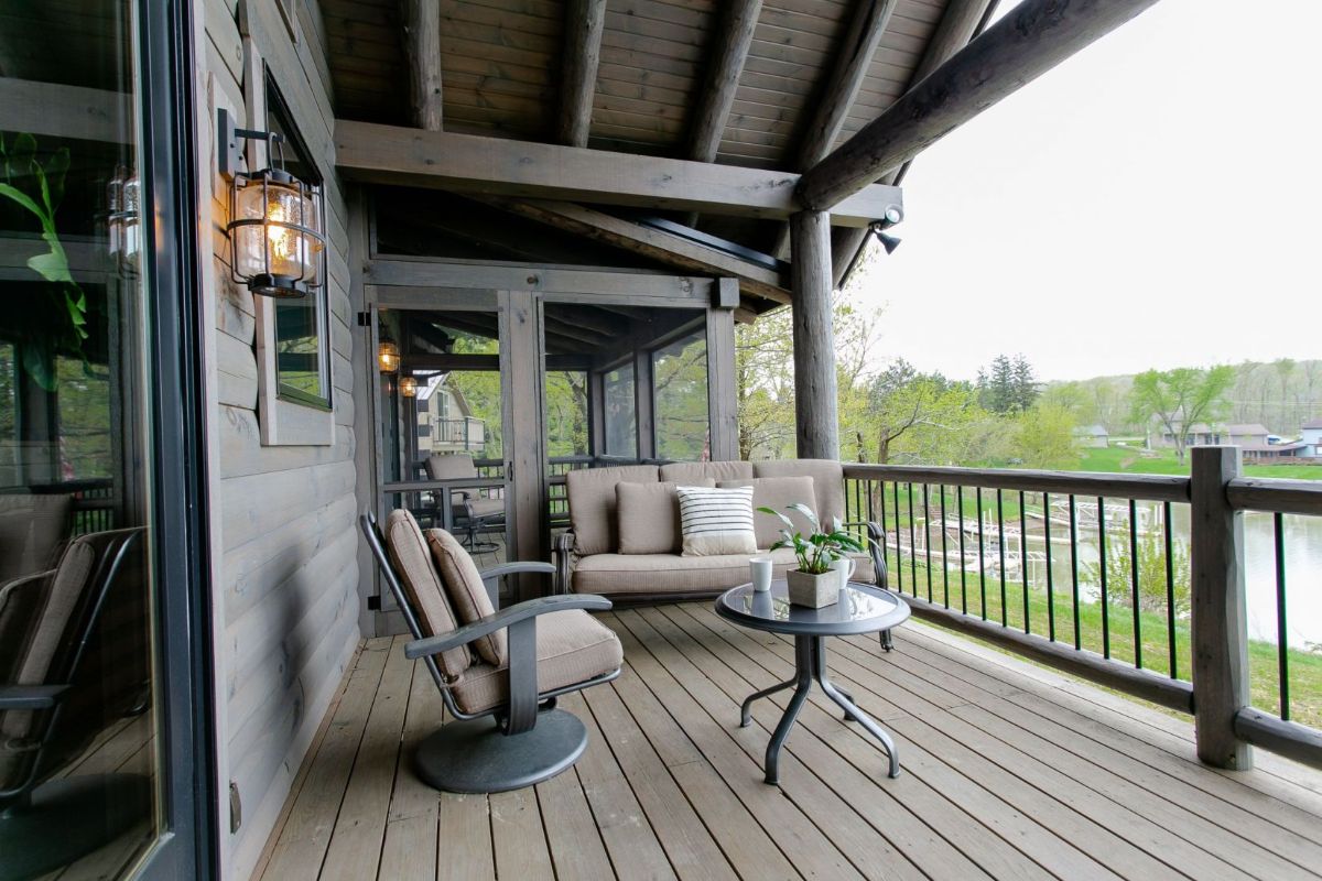 covered porch with chairs and bench next to screened room on cabin