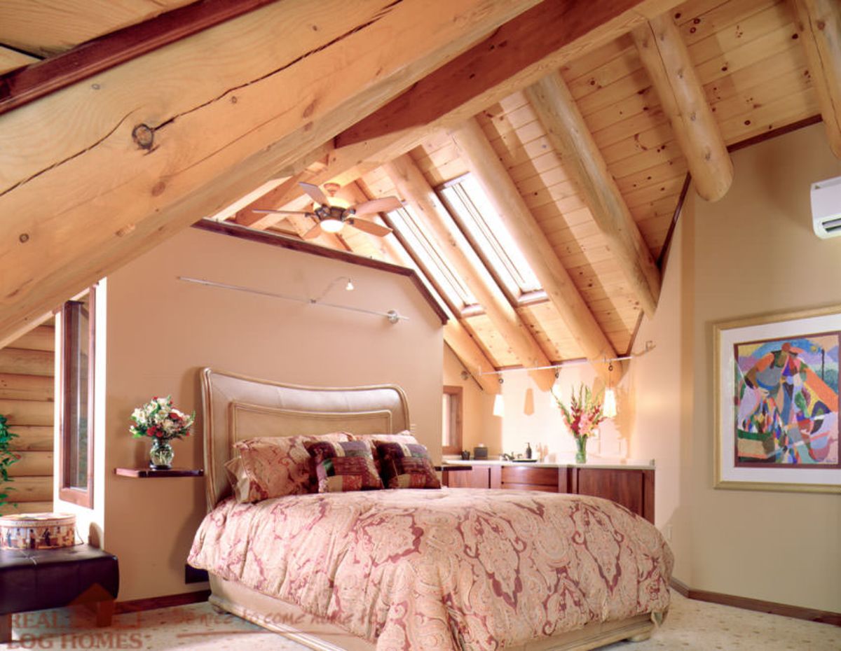 light colored bedding on large bed in log cabin loft room